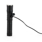 Black flashlight with a charging cable plugged in on a white background